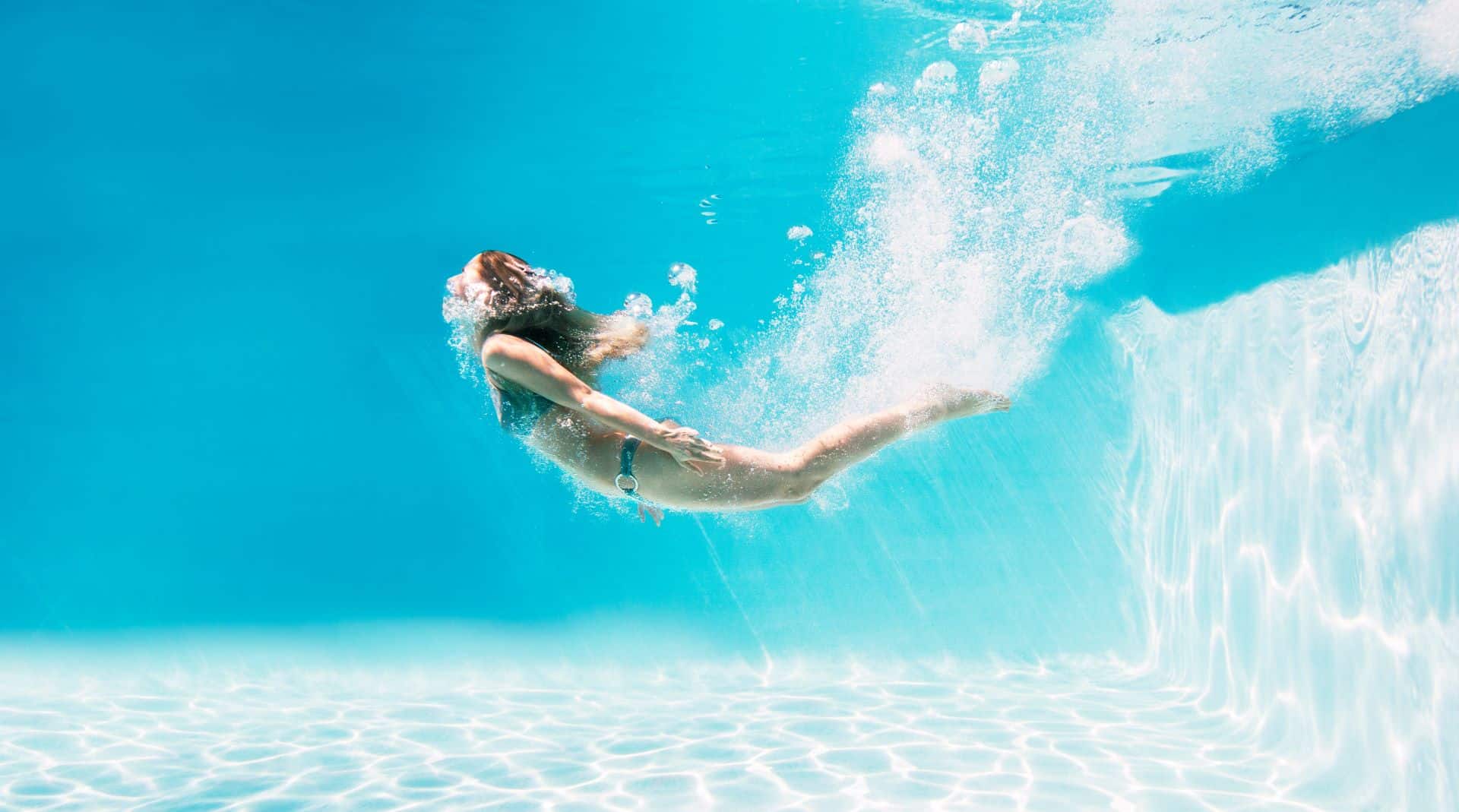 Frau schwimmt im Pool unter Wasser