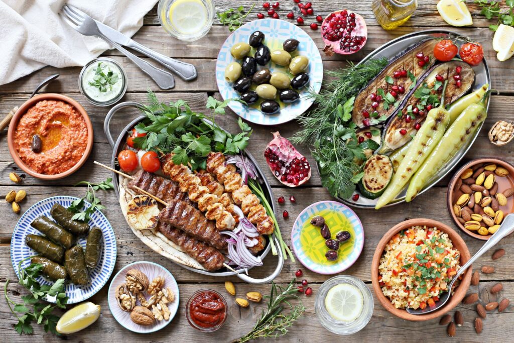 Vielfalt an mediterranen Meze mit Halloumi, Auberginen, Oliven und Dips auf Holzuntergrund