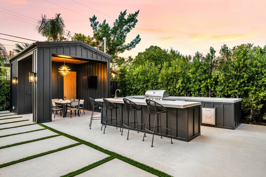 Design-Aussenkueche mit Grill, Bar und ueberdachter Lounge im modernen Garten