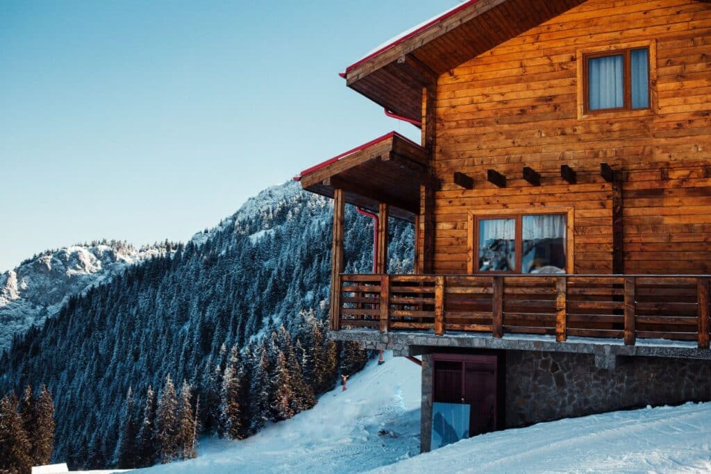 Eine Skihuette Oesterreich inmitten verschneiter Berge mit Holzfassade und Balkon vor alpiner Kulisse.