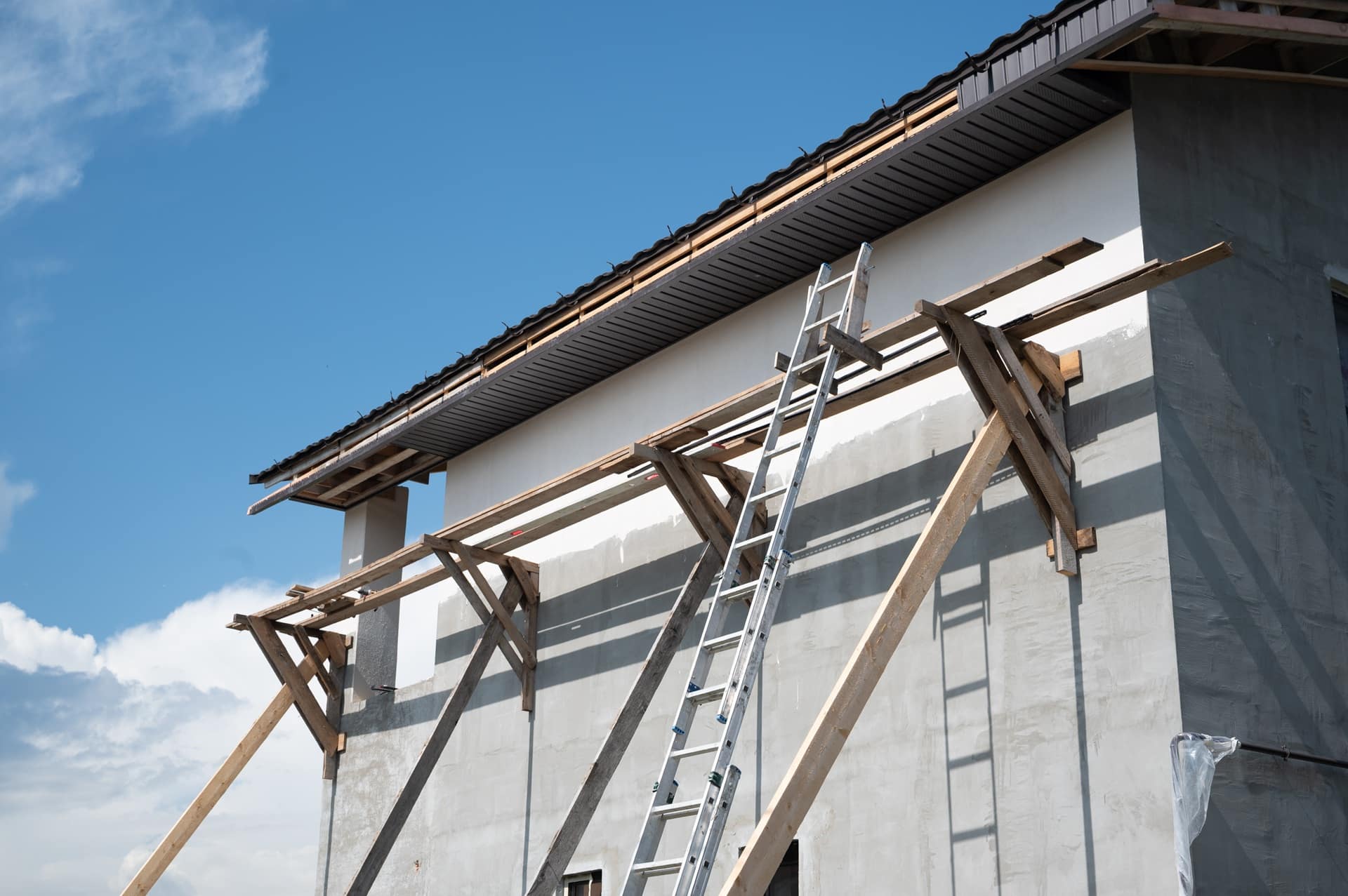 Hausfassade mit Leiter und Holzgerüst | Teleskop-Arbeitsbühne mieten