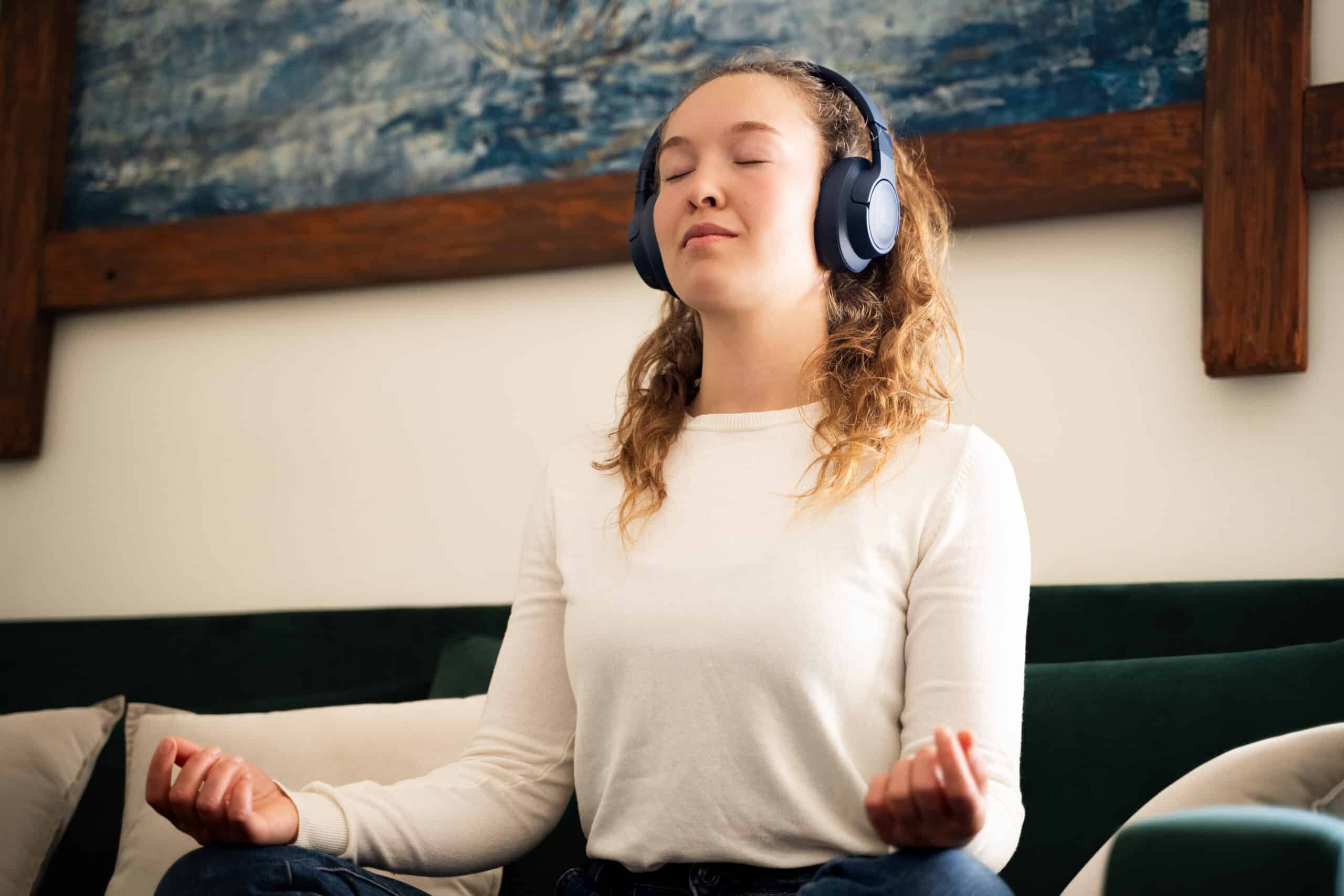 Frau meditiert mit Kopfhörern auf dem Sofa | Hydrafacial Behandlung